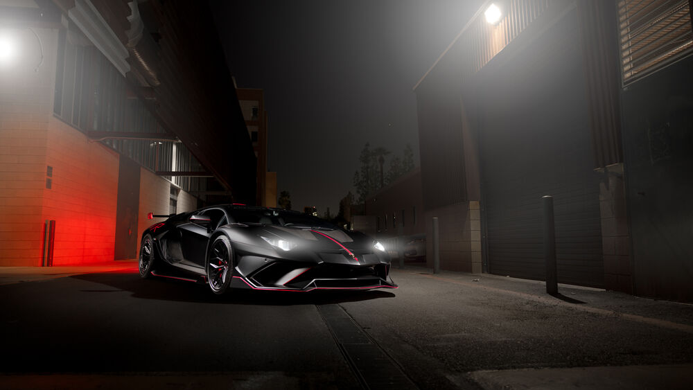 Обои для рабочего стола Черный Lamborghini с красными акцентами стоит в ночном городе