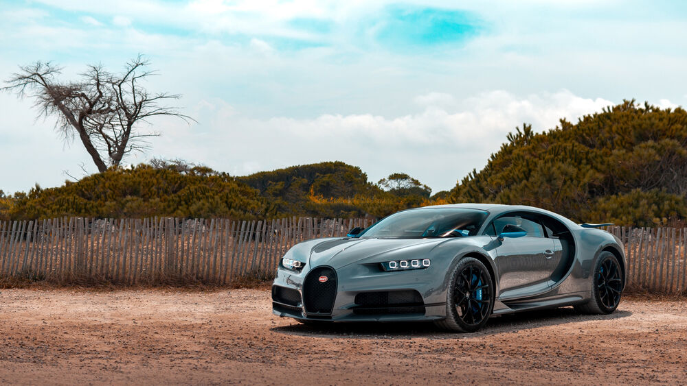 Обои для рабочего стола Зеркальный Bugatti Chiron на грунтовой дороге у забора