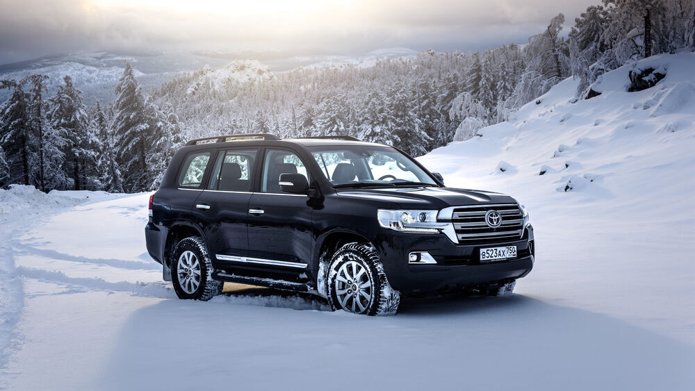 Обои для рабочего стола Toyota Landcruiser на заснеженной дороге среди леса покрытого снегом