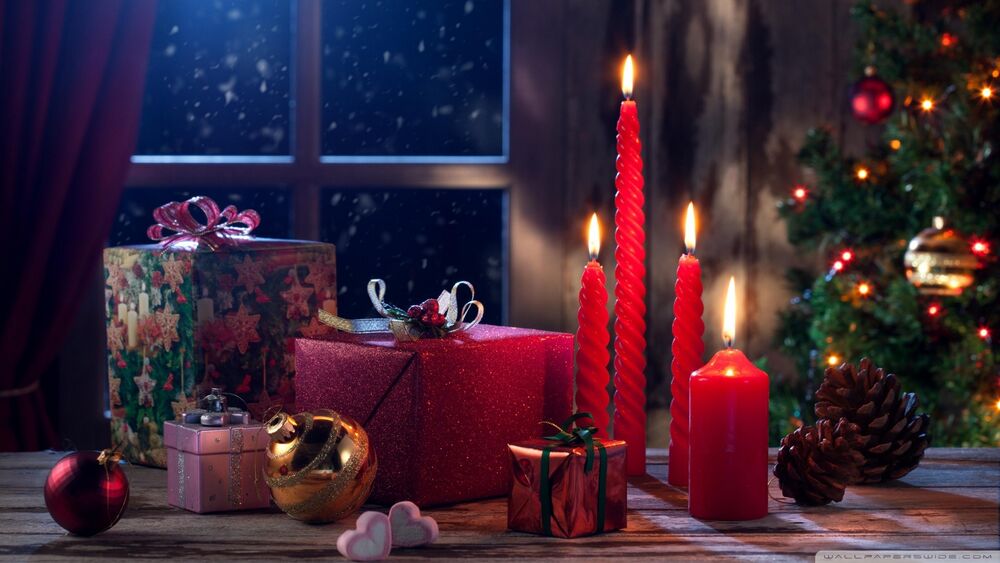 Обои для рабочего стола Подарки, горящие свечи, шары и шишки на полу в комнате с новогодней елкой
