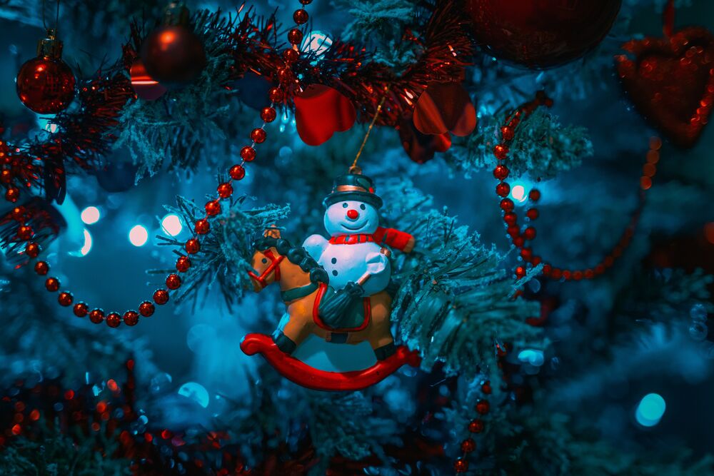 Обои для рабочего стола Снеговик на игрушечной лошадки, шары и бусы на новогодней елке