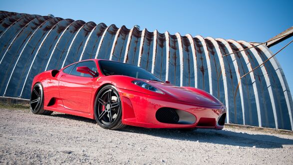 Обои на рабочий стол Красная Ferrari F430 на фоне конструкции