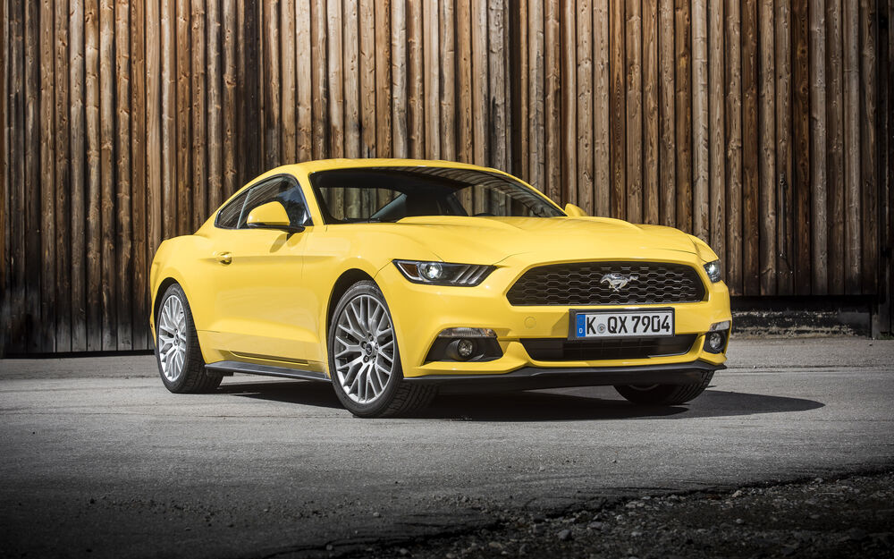 Обои для рабочего стола Желтый автомобиль Ford Mustang на фоне деревянного забора