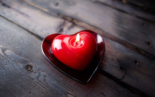 Обои на рабочий стол Красная свечка в форме сердца на деревянных досках