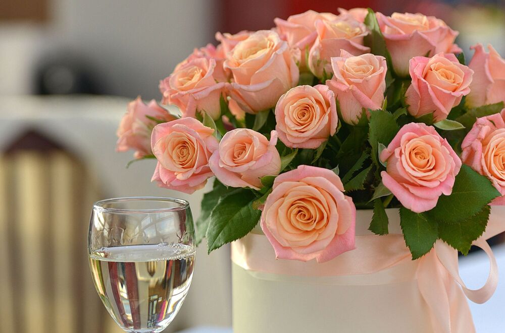 Обои для рабочего стола Букет розовых роз и бокал с напитком на переднем фоне