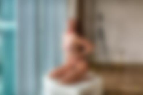 Обои на рабочий стол Модель Диша Шеметова топлес стоит на коленях на пуфе у окна в комнате и держится руками за трусики