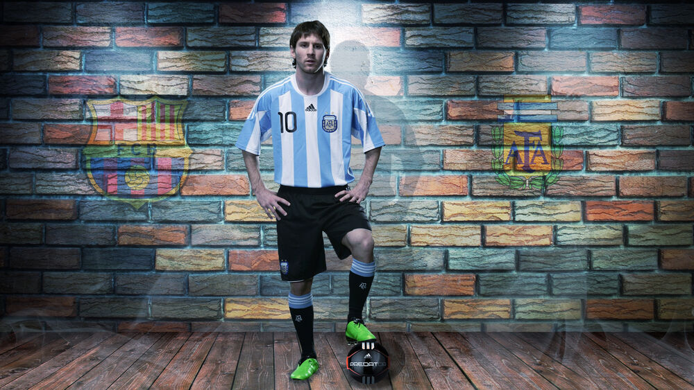 Обои для рабочего стола Звезда футбола Leonel Messi / Леонель Месси стоит с мячом в форме сборной Аргентины, на фоне расписанной стены с эмблемами ФК Барселона и Аргентины