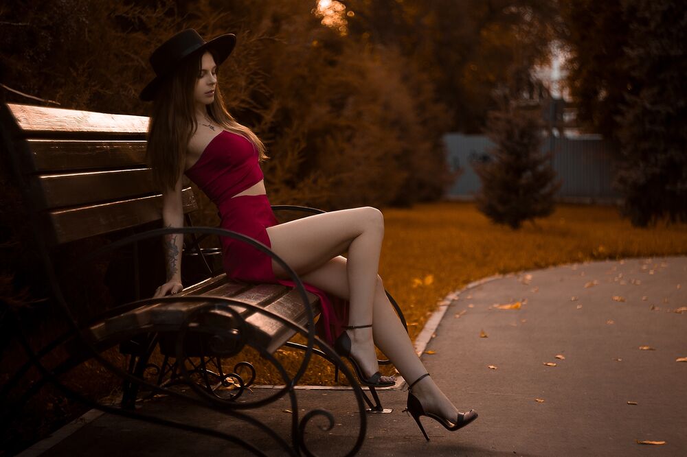 Очаровательная девушка в короткой юбке сидит на каменной скамейке с картой города