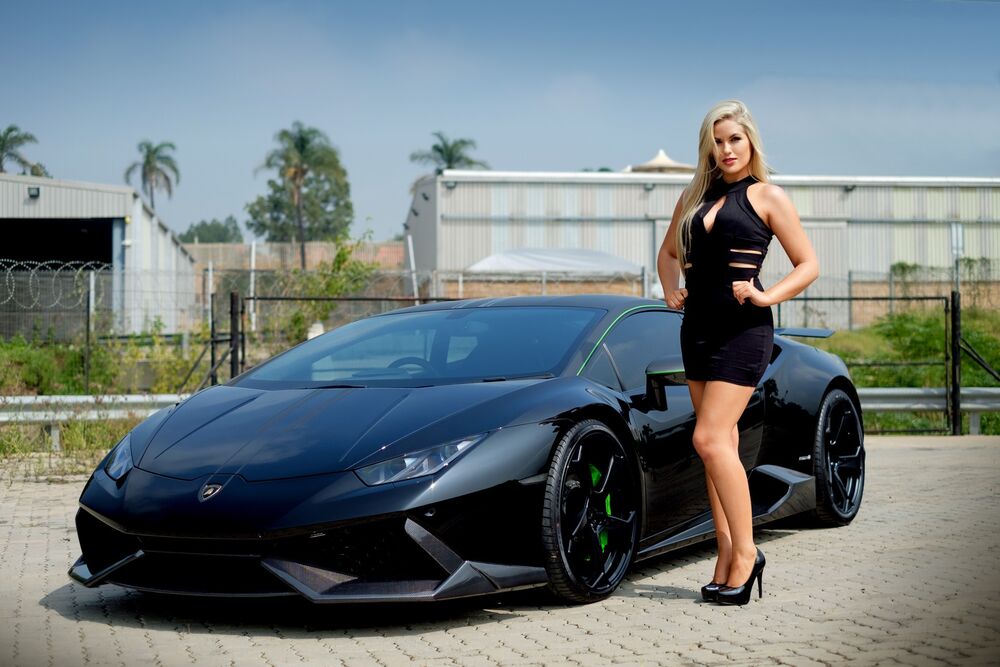 Обои для рабочего стола Модель Laura Bishop в черном платье стоит на площадке рядом с авто Lamborghini
