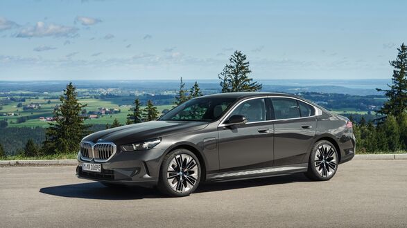Обои на рабочий стол Темно-серое BMW 5 Series 530e 2023 в ясную погоду на холме