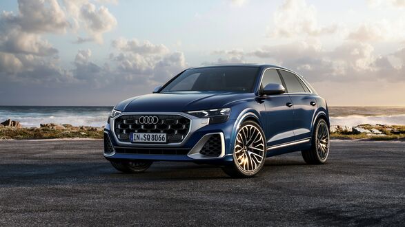 Обои на рабочий стол Синяя Audi SQ8 TFSI 2023 на каменистом побережье под кучевыми облаками