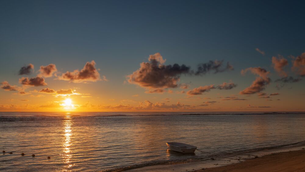 Обои для рабочего стола Одинокая лодка на берегу океана на закате солнца