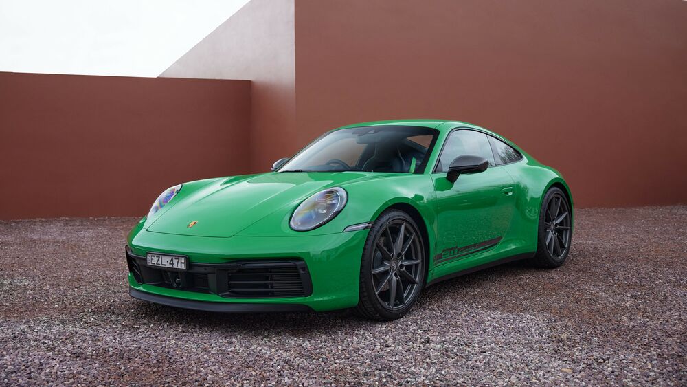 Обои для рабочего стола Зеленый Porsche 911 Carrera T 2023 на фоне красной стены