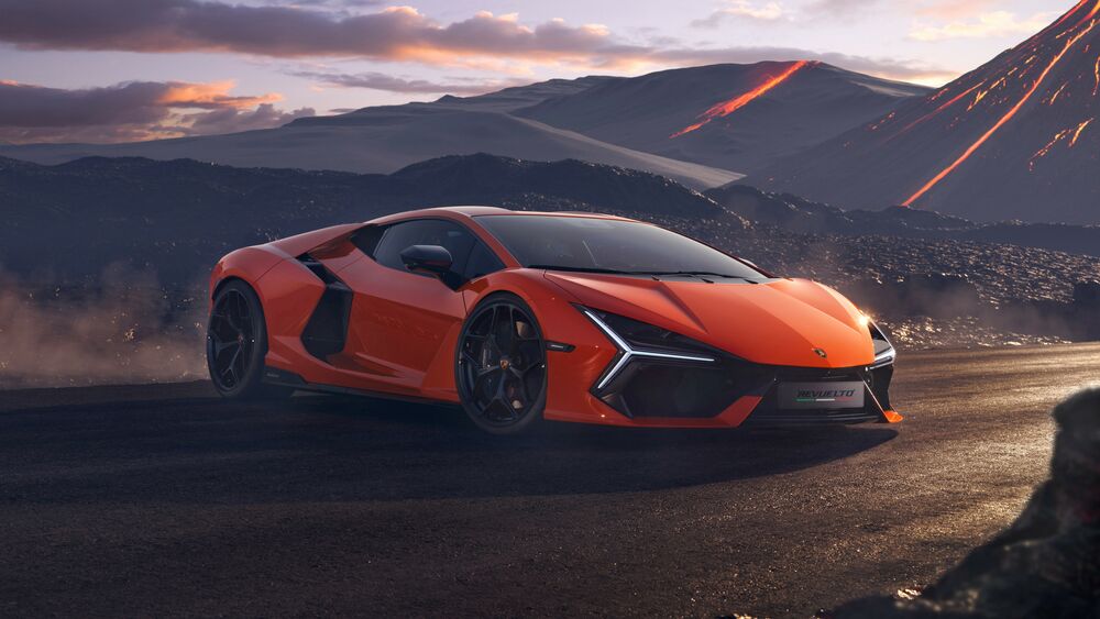 Обои для рабочего стола Оранжевый Lamborghini Revuelto на дороге у пепельных гор