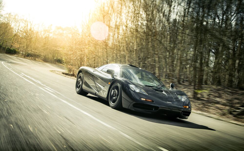 Обои для рабочего стола McLaren темного цвета едет по лесной дороге