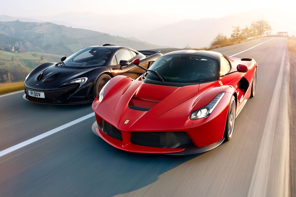 Обои для рабочего стола Черный McLaren и красный Ferrari едут по дороге за городом на высокой скорости