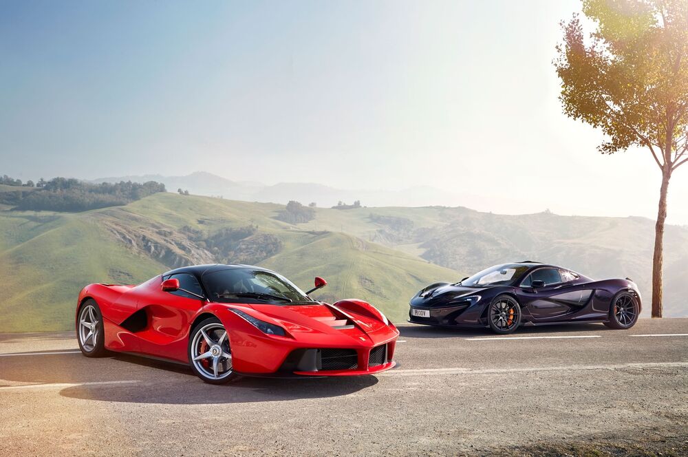 Обои для рабочего стола Черный McLaren и красный Ferrari на фоне зеленого ландшафта