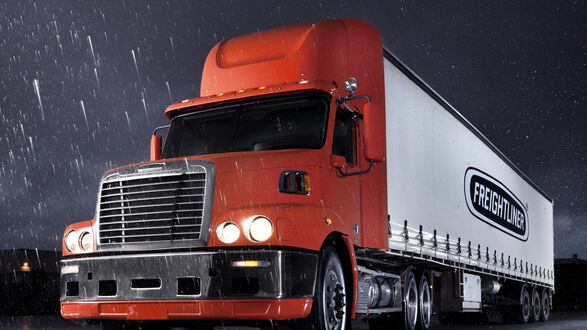 Обои на рабочий стол Оранжевый грузовик Freightliner стоит ночью на трассе
