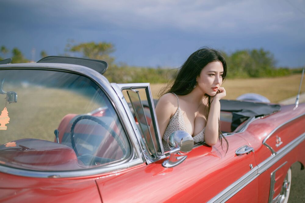 Обои для рабочего стола Красивая азиатка в бежевом платье сидит в красном кабриолете