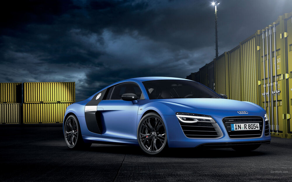 Обои для рабочего стола Спортивный автомобиль Audi R8 синего цвета стоит среди желтых контейнеров на фоне пасмурного неба