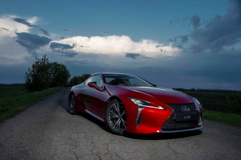 Обои для рабочего стола Красный автомобиль Лексус / Lexus LC стоит на дороге на фоне вечернего неба с облаками