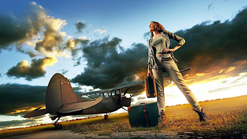 Обои для рабочего стола Девушка с чемоданами стоит рядом с самолетом на закате