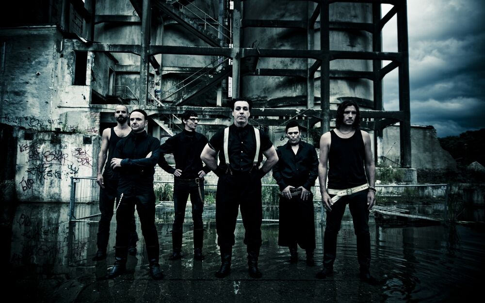 Обои для рабочего стола 5 мужчин участники группы Rammstein на фоне заброшенного индустриального здания в пасмурную погоду