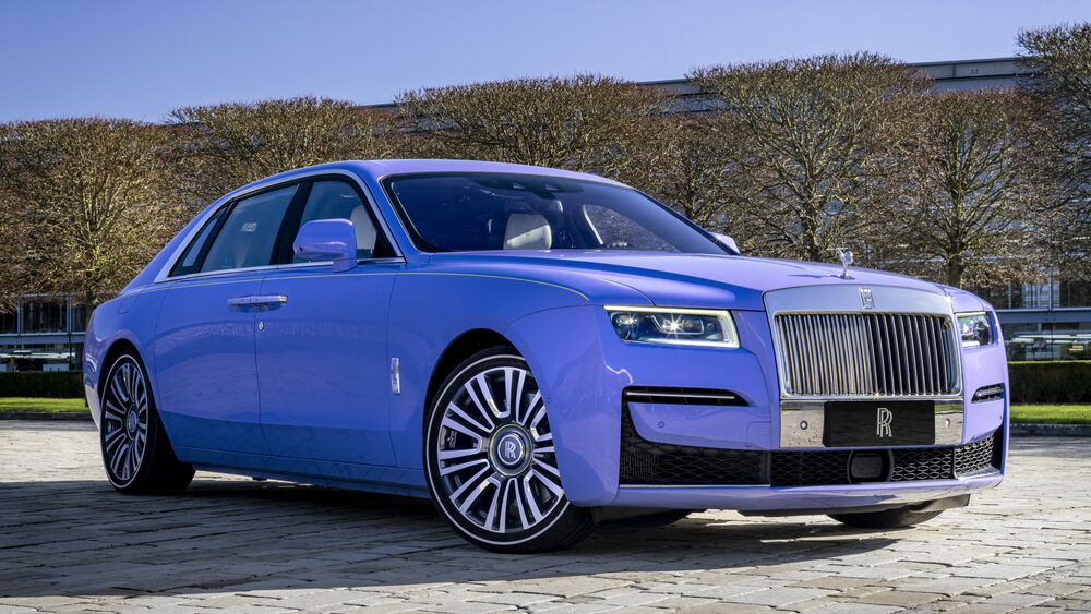 Обои для рабочего стола Сиреневый Rolls-royce Ghost на фоне деревьев на площади города