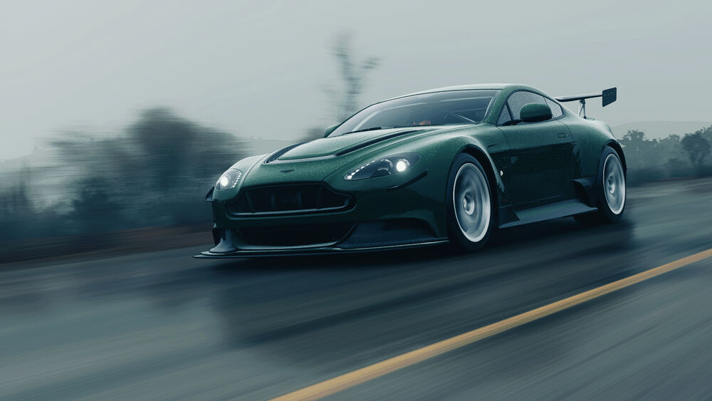Обои для рабочего стола Темно-синемзеленый Aston Martin мчится по шоссе в пасмурную погоду