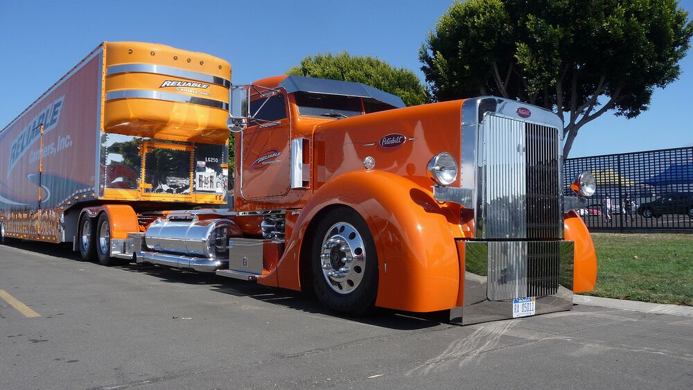 Обои для рабочего стола Оранжевый грузовик Peterbilt с прицепом на дороге