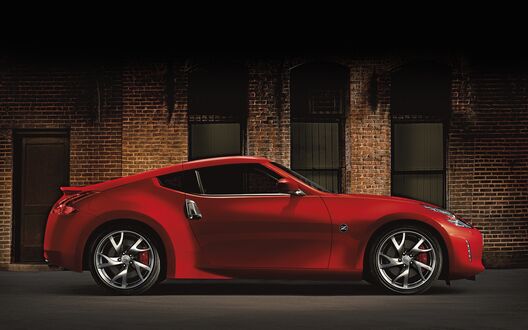 Обои на рабочий стол Крассный Nissan 370Z у кирпичного здания сбоку