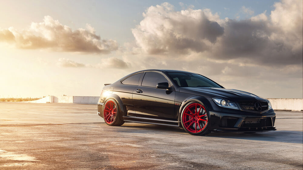 Обои для рабочего стола Черный Mercedes benz c 63 amg на треке под облачным небом