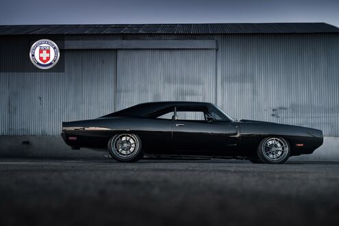 Обои на рабочий стол Черный Dodge Charger стоит на дороге возле ангара