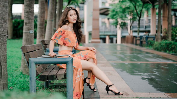 Обои на рабочий стол Пак Синхе / Park Shin-hye — южнокорейская певица в оранжевом цветном платье сидит на скамейке в парке