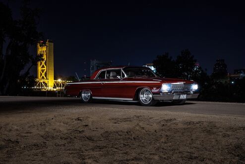 Обои на рабочий стол Красный Chevrolet Impala стоит на ночной дороге с включенными фарами