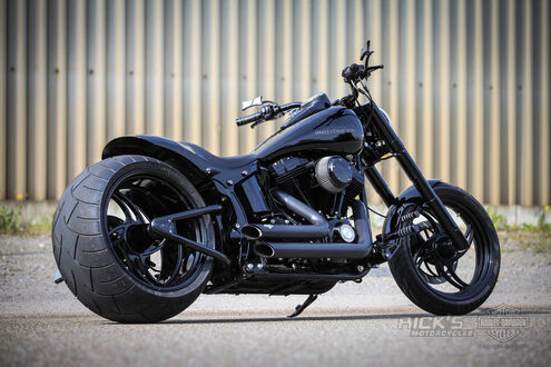 Обои на рабочий стол Черный мотоцикл Harley Davidson стоит на стоянке на фоне серого забора