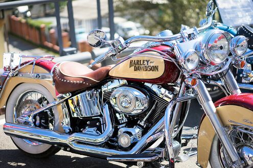 Обои на рабочий стол Красно-желтый мотоцикл Harley Davidson на фоне домов