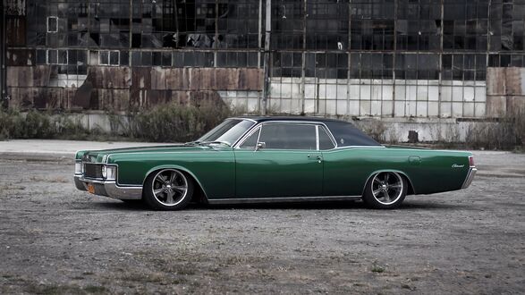 Обои на рабочий стол Зеленый Lincoln Continental стоит на стоянке на фоне старого ангара
