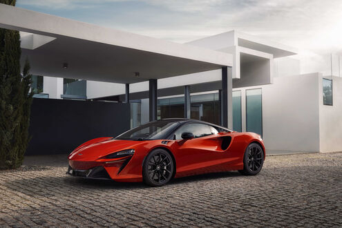 Обои на рабочий стол Красный McLaren Artura возле белого здания