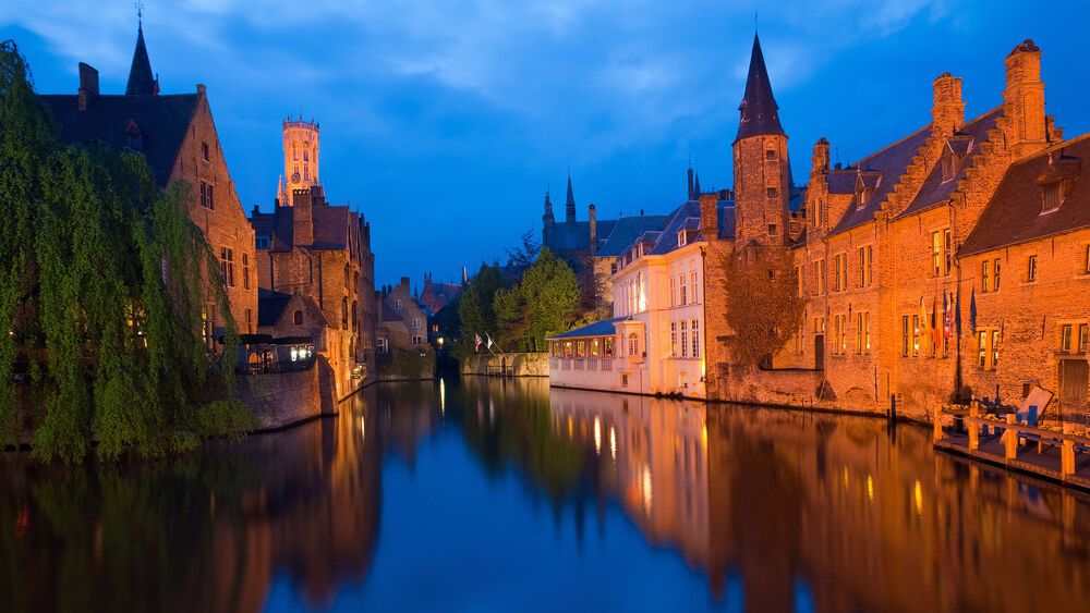 Обои для рабочего стола Город Брюгге / Bruges, Бельгия / Belgium, вечер, каналы с отражением старинных зданий на фоне голубого неба и подсвеченных фасадов