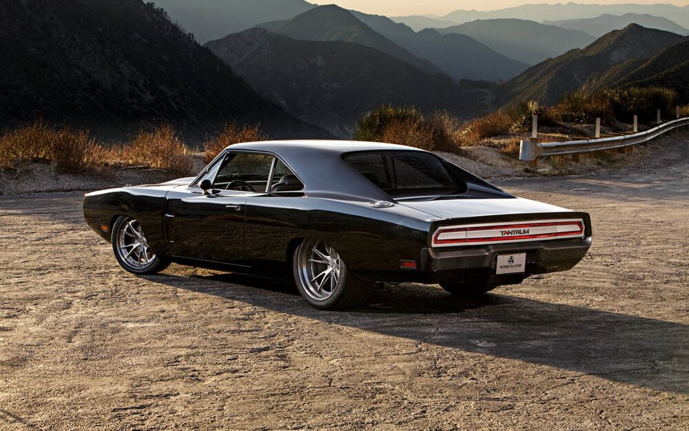 Обои для рабочего стола Черный Dodge Charger стоит на стоянке на фоне гор