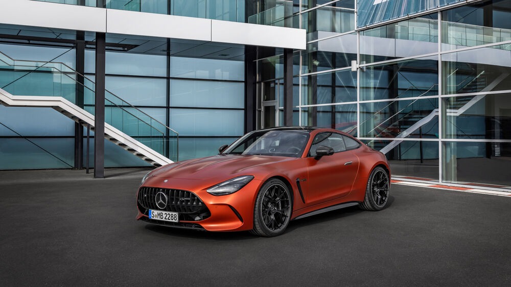 Обои для рабочего стола Красный автомобиль Mercedes-AMG GT 63 S E Performance 2024 года у стеклянного здания с лестницами