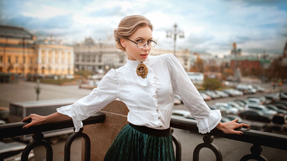Обои для рабочего стола Модель Olga в белой блузке и в юбке стоит на балконе городского здания