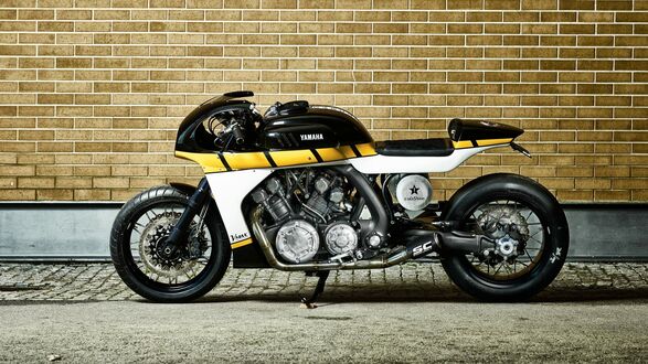 Обои на рабочий стол Черно-желтый мотоцикл V max Yamaha с округлыми обводами стоит у кирпичной стены на асфальте