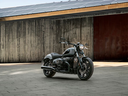 Обои на рабочий стол Мотоцикл Bmw r-18 черного цвета стоит на площадке перед бетонной стеной и крышей с солнечными панелями