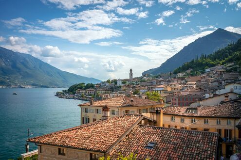 Обои на рабочий стол Город Лимоне-суль-Гарда / Limone sul Garda находится у озера Гарда на фоне гор Италия / Italy в солнечный день
