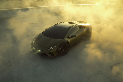 Обои на рабочий стол Lamborghini Huracan Sterrato в клубах густого дыма на бетонной площадке на закате