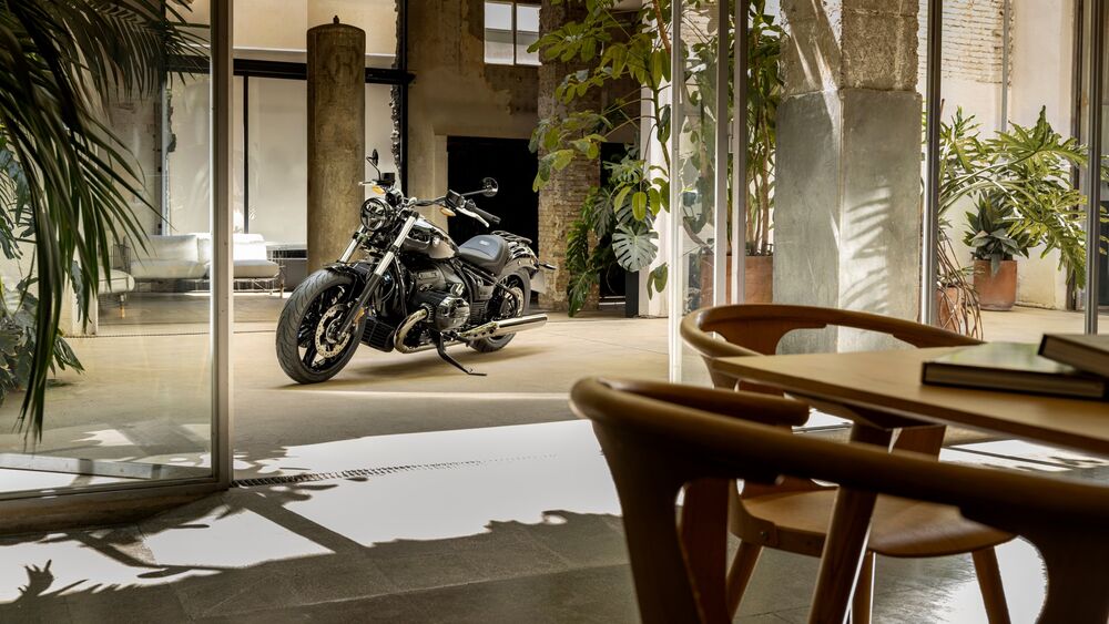 Обои для рабочего стола Мотоцикл BMW R 18 стоит на полу современной гостиной с деревянной мебелью и растениями у стеклянных дверей