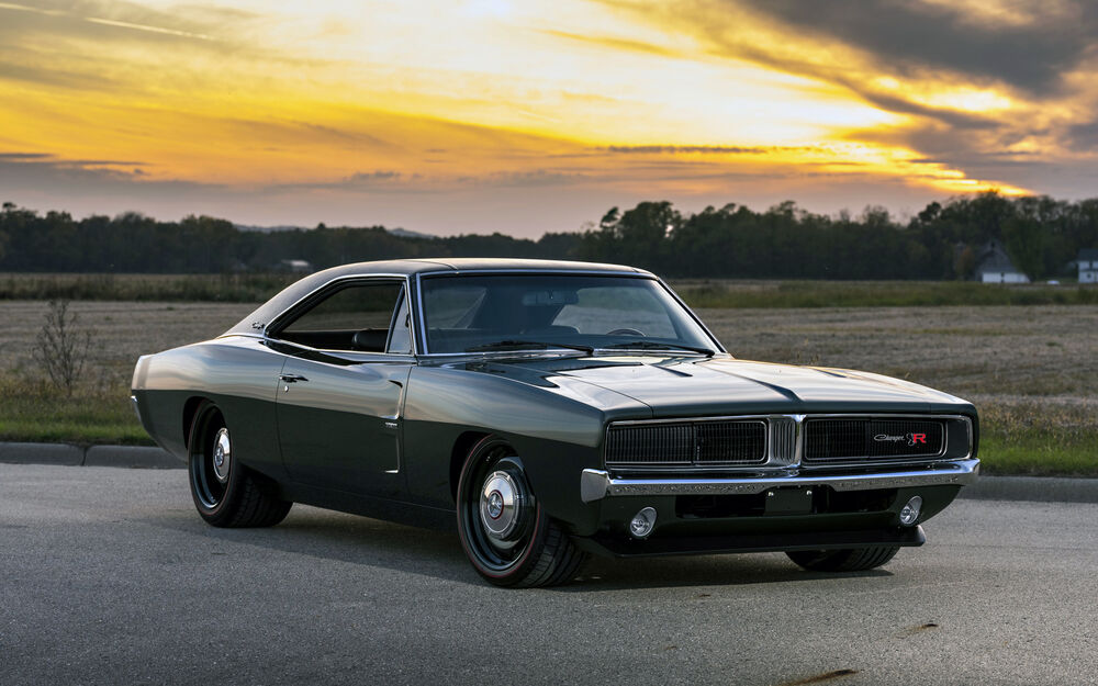 Обои для рабочего стола Черный Ретро-автомобиль Dodge Charger стоит на асфальтированной дороге на фоне поля и закатного неба