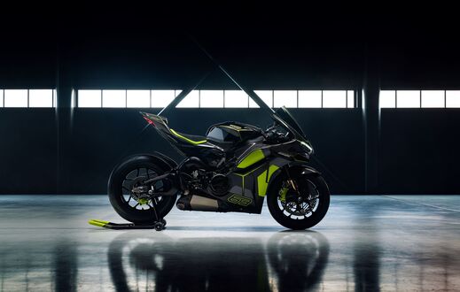 Обои на рабочий стол Мотоцикл Ducati / Дукати черного цвета с зелеными деталями стоит в ангаре на фоне больших окон при искусственном освещении